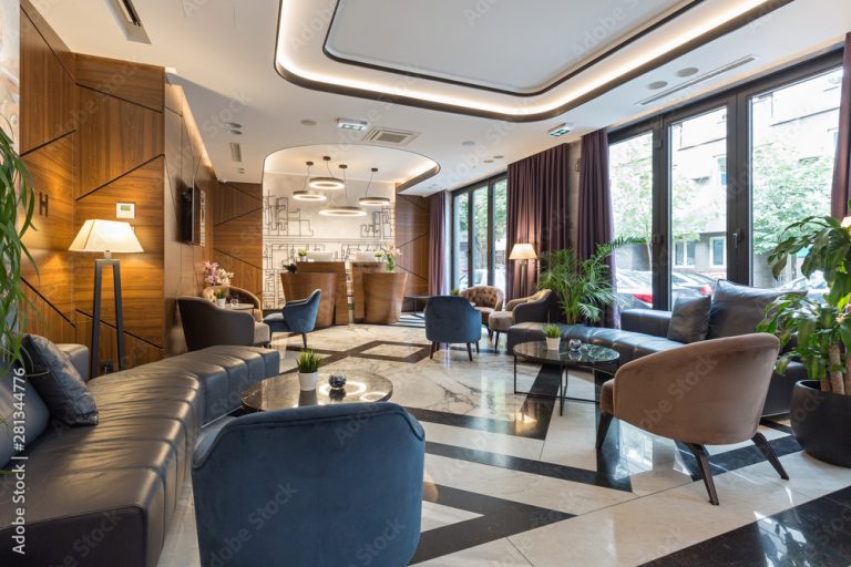 Lobby eines Hotels mit Sitzbereichen und großen Fenstern.