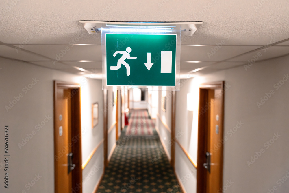 Beleuchtetes Fluchtwegzeichen in einem Hotelflur.